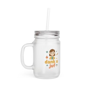 Op de afbeelding: Een heldere glazen pot met een zilveren deksel en handvat, met een wit rietje. De pot heeft een kleurrijke afbeelding van een leraar met de tekst "dank u juf" in oranje en groen. Perfect voor koude dranken.