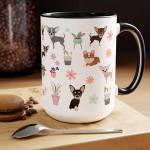 May include: White ceramic mug with a black rim and handle. The mug features a repeating pattern of small potted plants, flowers, and cartoon chihuahua dogs in various colors.
