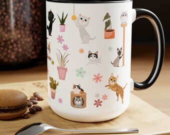 May include: White ceramic mug with a black rim and handle. The mug features a repeating pattern of cartoon cats, plants, and flowers.