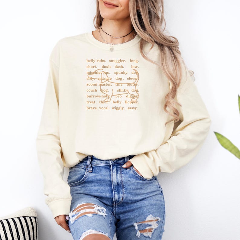 monochromatic design on comfort colors 
long sleeve tshirt with a word collage featuring an outline of a dachshund in background