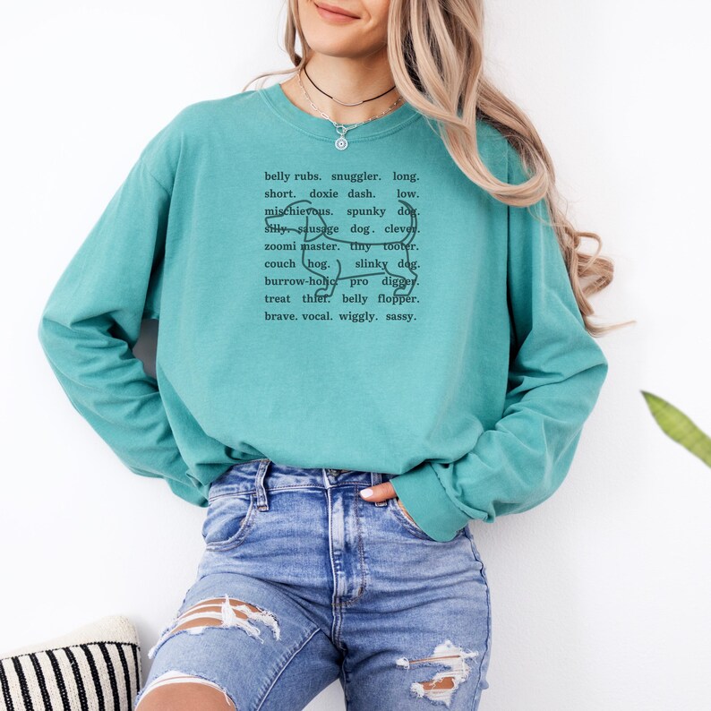 monochromatic design on comfort colors 
long sleeve tshirt with a word collage featuring an outline of a dachshund in background