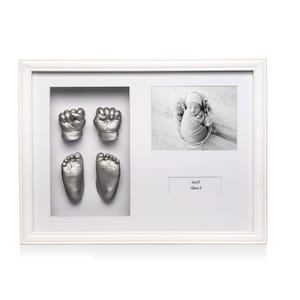 May include: White frame with a silver baby hand and footprint imprint, a black and white photo of a baby, and a nameplate with the text "Rose" and "2023".