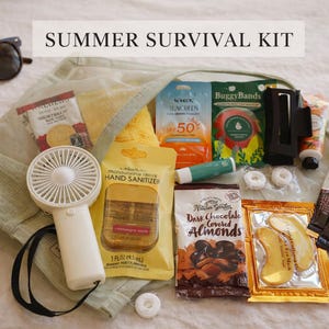 May include: A summer survival kit with sunglasses, a portable fan, sunscreen, hand sanitizer, snacks, and other essentials. The kit is contained in a mesh bag and includes the text "SUMMER SURVIVAL KIT".