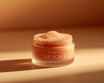May include: A small, open jar of lip scrub with a light orange hue. The jar is labeled "LY 3OMANCE LIP SCRUB" with additional text. The scrub itself has a granular texture and is topped with a mound of the same color. The background is a warm, neutral tone.