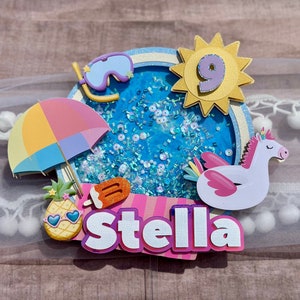 May include: A colorful cake topper with a blue pool, a unicorn float, a pineapple, an ice cream cone, a beach umbrella, a yellow sun with the number 9, and the name Stella.