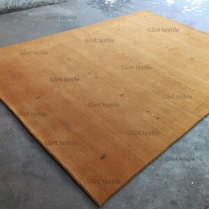 May include: A large, rectangular, mustard yellow rug with the text "Glint textile" repeated throughout the rug.