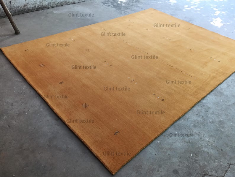 May include: A large, rectangular, mustard yellow rug with the text "Glint textile" repeated throughout the rug.