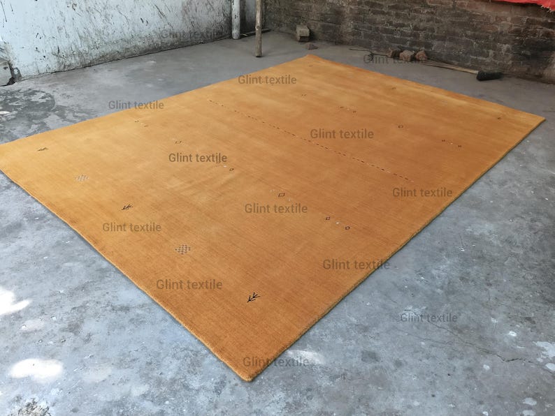 May include: A large, rectangular, light brown rug with a subtle texture. The rug is lying flat on a concrete floor.
