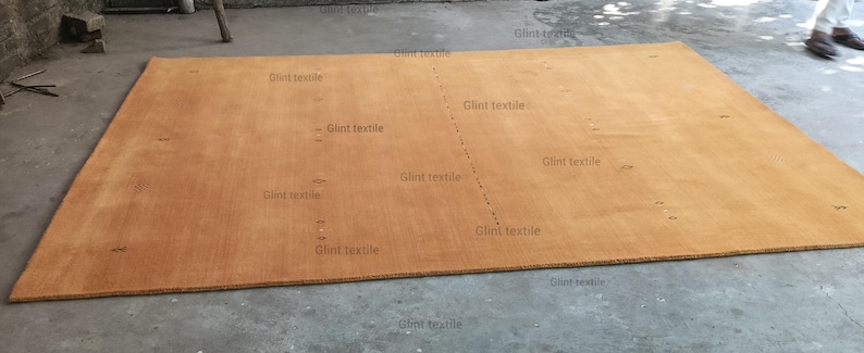May include: A large, rectangular, light brown rug with a subtle texture. The rug is made of natural fibers and has a simple, elegant design.