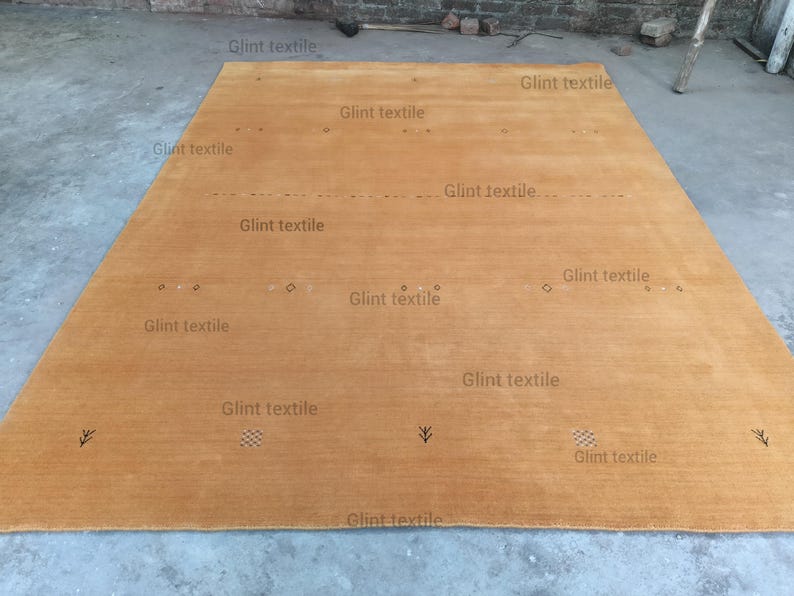 May include: A large, rectangular, light brown rug with a subtle texture. The rug has a simple design with a few small, dark markings.