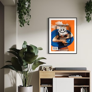 May include: Framed art print featuring a surreal collage. The artwork has an orange background with a blue inflatable ring and a white smiley face. A barcode is visible on the bottom left. The print is displayed on a wall with plants and a wooden cabinet.