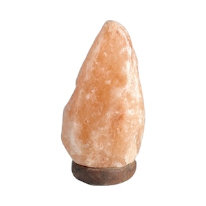 May include: A large, natural Himalayan salt lamp with a warm orange hue. The lamp is sitting on a wooden base.