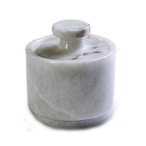 May include: A white marble butter dish with a round, cylindrical base and a matching lid with a small, circular handle. The dish has a smooth, polished finish and a natural, veined pattern.