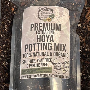 May include: A clear plastic bag filled with a dark brown potting mix for Hoya plants. The bag has a white label with the text "Rooting for you Plant Nursery Eugene Oregon", "Premium Extra Fine Hoya Potting Mix", "100% Natural & Organic", "Soil Free, Peat Free & Perlite Free", "Handcrafted Small Batch Plant Care", and "www.rootingforyouplantnursery.com".