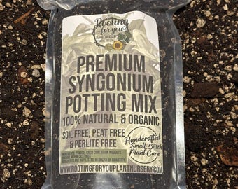 May include: A clear plastic bag filled with a dark brown potting mix for Syngonium plants. The bag has a white label with the text "Rooting for you Plant Nursery", "Premium Syngonium Potting Mix", "100% Natural & Organic", "Soil Free, Peat Free & Perlite Free", "Handcrafted Small Batch Plant Care", and "www.rootingforyouplantnursery.com".