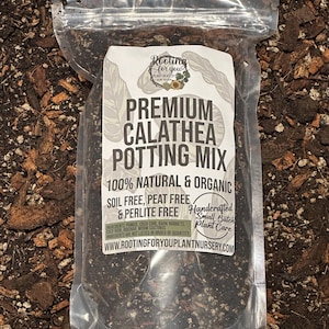 May include: A clear plastic bag filled with a dark brown potting mix for Calathea plants. The bag has a white label with the text "Rooting for you Plant Nursery", "Premium Calathea Potting Mix", "100% Natural & Organic", "Soil Free, Peat Free & Perlite Free", "Handcrafted Small Batch Plant Care", and "www.rootingforyouplantnursery.com".