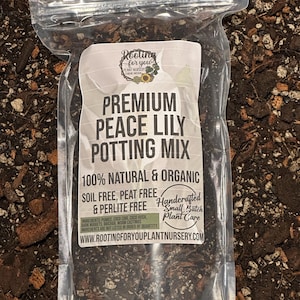 May include: A clear plastic bag filled with a dark brown potting mix for peace lilies. The bag has a white label with the text "Rooting for you Plant Nursery", "Premium Peace Lily Potting Mix", "100% Natural & Organic", "Soil Free, Peat Free & Perlite Free", "Handcrafted Small Batch Plant Care", and "www.rootingforyouplantnursery.com".