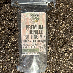 May include: A clear plastic bag filled with a dark brown potting mix. The bag has a white label with the text "Rooting for you Plant Nursery" and "Premium Chenille Potting Mix 100% Natural & Organic Soil Free, Peat Free & Perlite Free Handcrafted Small Batch Plant Care WWW.ROOTINGFORYOUPLANTNURSERY.COM".