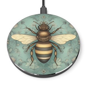 May include: Round wireless charger with a detailed illustration of a bee. The bee is brown and yellow, with cream-colored wings, set against a teal background with a floral pattern. The charger has a black rim and a black power cord.