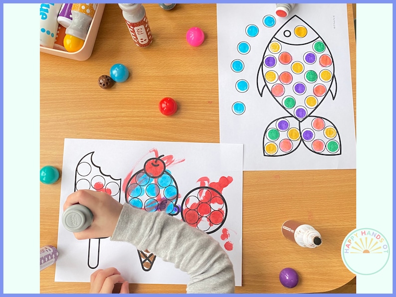 May include: A child is using dot markers to color in a picture of an ice cream cone and a popsicle. The picture is on a white sheet of paper. There are also dot markers and a fish picture on the table.