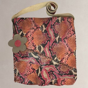 May include: A pink, orange and black snakeskin shoulder bag with a brown flower accent. The bag has a long strap and a flap closure.