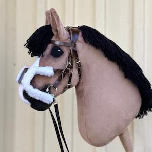 Peut inclure: Une t&ecirc;te de cheval en peluche marron et noire avec une crini&egrave;re noire et une bride en cuir marron. Le cheval a un museau blanc et un nez noir. Le cheval est attach&eacute; &agrave; une r&ecirc;ne en cuir noir.