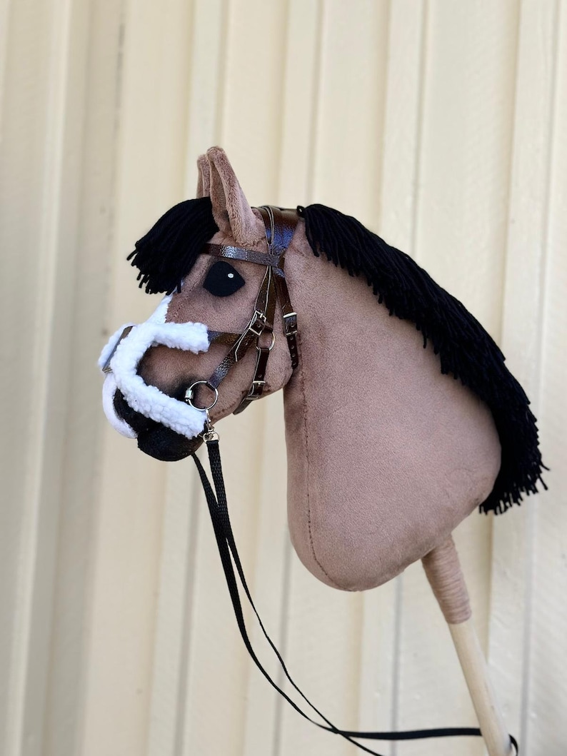 Peut inclure: Une t&ecirc;te de cheval marron et blanche avec une crini&egrave;re noire et une bride en cuir marron. La t&ecirc;te de cheval est fix&eacute;e &agrave; un b&acirc;ton en bois.