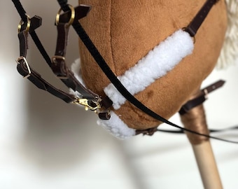 May include: A brown plush rocking horse with a white mane and tail. The horse has a black bridle with brown leather straps and a gold buckle. The horse is on a wooden stand.