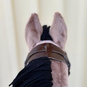 Peut inclure: Un jouet en peluche en forme de cheval brun avec une crini&egrave;re et une queue noires. Le cheval porte un bridon en cuir brun avec une boucle.