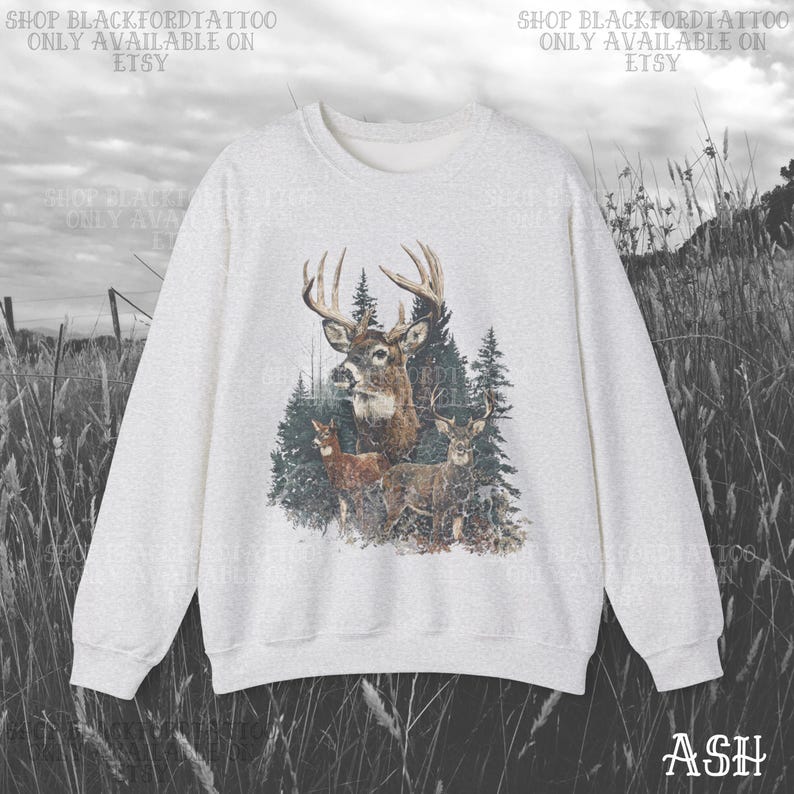 May include: Ash-coloured sweatshirt with a detailed graphic of a buck with large antlers and several deer in a forest setting. The text "SHOP BLACKFORDTATTOO ONLY AVAILABLE ON ETSY" is printed at the top. The word "ASH" is printed at the bottom right.