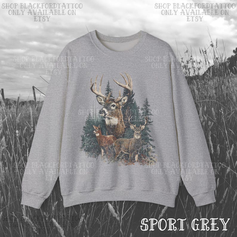 May include: Sport grey sweatshirt with a detailed illustration of a buck with large antlers and two deer in a forest setting. The text "SHOP BLACKFORDTATTOO ONLY AVAILABLE ON ETSY" is printed around the top of the sweatshirt.