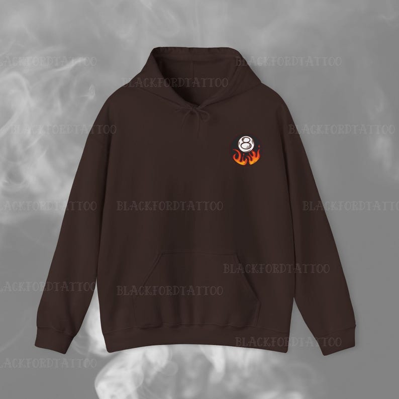 May include: A brown hoodie with a pocket on the front. The hoodie has a white 8-ball with flames on it.