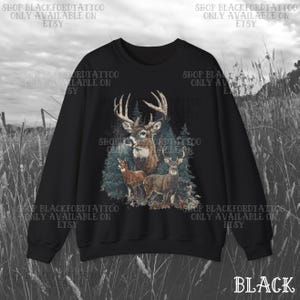 May include: Black sweatshirt with a detailed illustration of deer in a forest. The design features a large buck with antlers, two smaller deer, and evergreen trees. The word "BLACK" is at the bottom right.