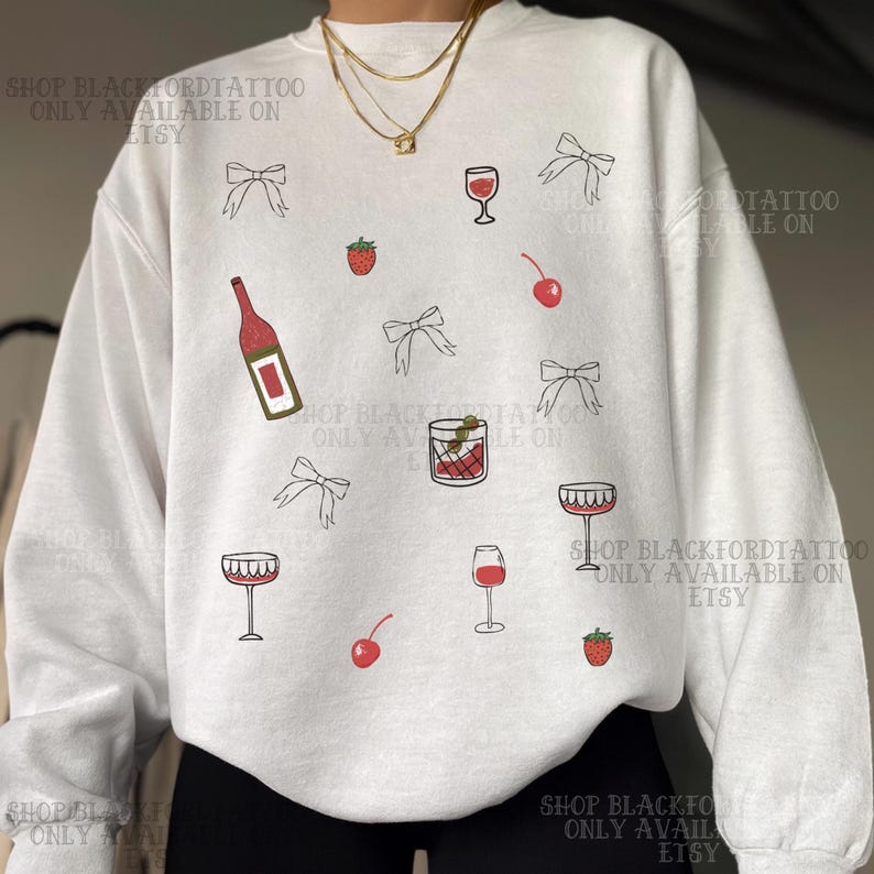 May include: White sweatshirt with a repeating pattern of wine glasses, bows, cherries, strawberries, and a wine bottle. The design is in black and red. The text "SHOP BLACKFORDTATTOO ONLY AVAILABLE ON ETSY" is printed on the sweatshirt.