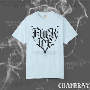 May include: Light blue t-shirt with a black gothic-style heart design that reads "FUCK ME". The shirt also has the text "SHOP BLACKFORDTATTOO ONLY AVAILABLE ON ETSY" printed around the design. The word "CHAMBRAY" is printed at the bottom.