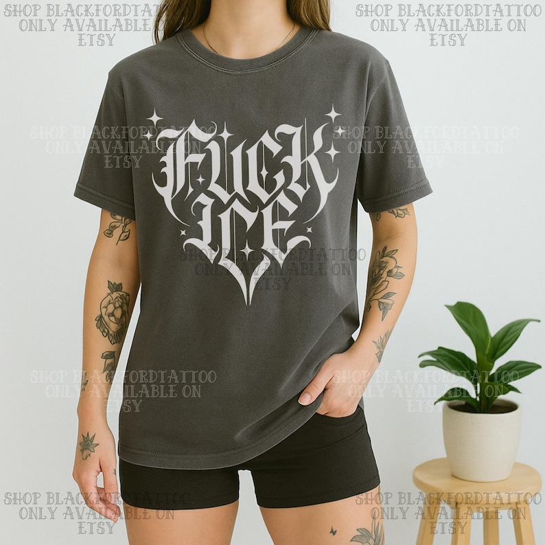 May include: Dark gray t-shirt with a white gothic-style graphic that reads "Fuck Me" in a heart shape. The shirt is short-sleeved and has a crew neck. The text "SHOP BLACKFORDTATTOO ONLY AVAILABLE ON ETSY" is printed around the image.