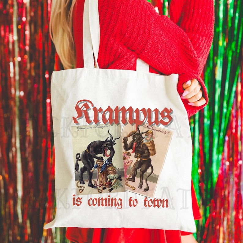 May include: A white tote bag with the text "Krampus is coming to town" in red. The bag features two vintage illustrations of Krampus, a horned figure from European folklore, with the text "Gruss vom Krampus" and "B&ouml;sewichte!" in German.