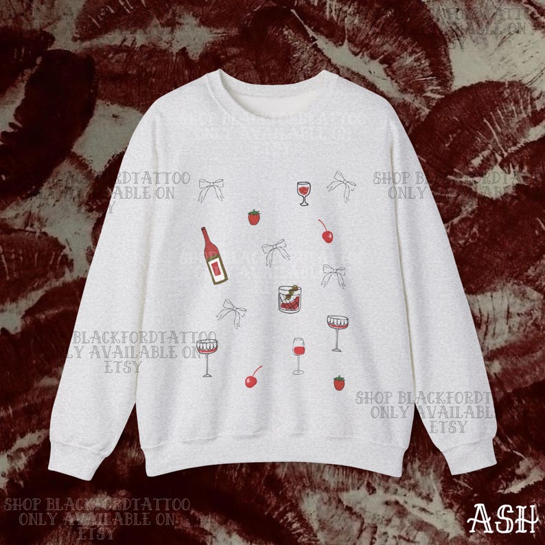 May include: A light gray sweatshirt with a repeating pattern of wine glasses, cherries, strawberries, bows, and a wine bottle. The text "SHOP BLACKFORDTATTOO ONLY AVAILABLE ON ETSY" is printed on the sweatshirt.