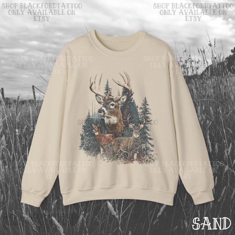 May include: A sand-coloured sweatshirt with a detailed illustration of deer in a forest setting. The graphic includes a buck with large antlers, smaller deer, and evergreen trees. The text "SHOP BLACKFORDTATTOO ONLY AVAILABLE ON ETSY" is printed around the design.