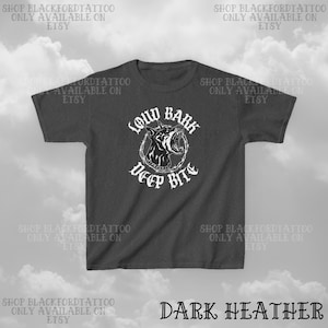 Puede incluir: Camiseta gris oscuro con un gr&aacute;fico blanco de la cabeza de un perro gru&ntilde;endo dentro de un c&iacute;rculo de alambre de p&uacute;as. El texto "LOUD BARK DEEP BITE" est&aacute; debajo. El texto "DARK HEATHER" est&aacute; en la parte inferior.