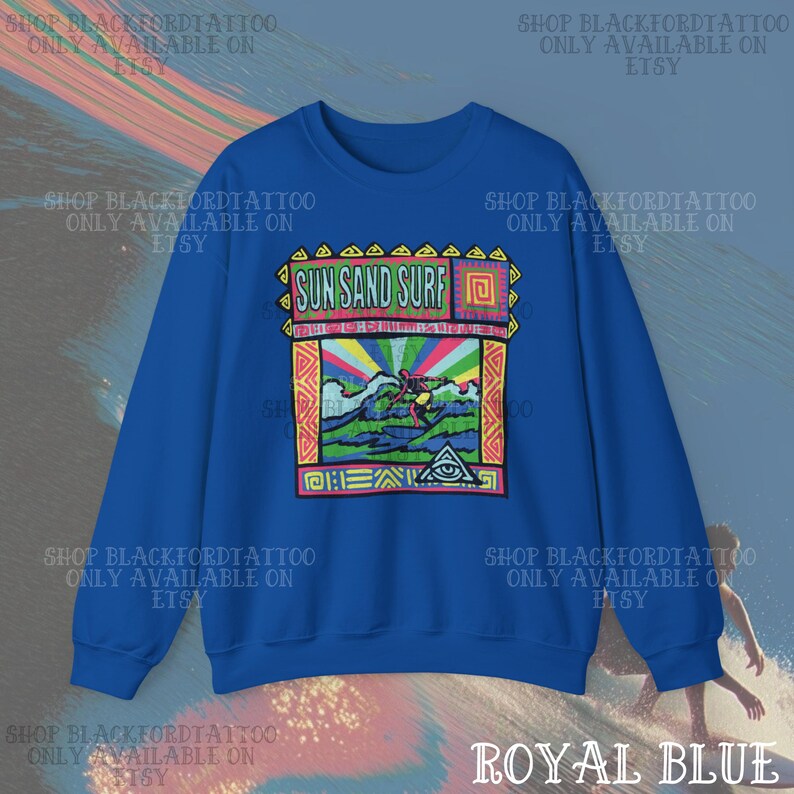 May include: Royal blue sweatshirt with a colorful graphic that reads "Sun Sand Surf." The graphic features a surfer, waves, and a rainbow. The sweatshirt is a crew neck style.