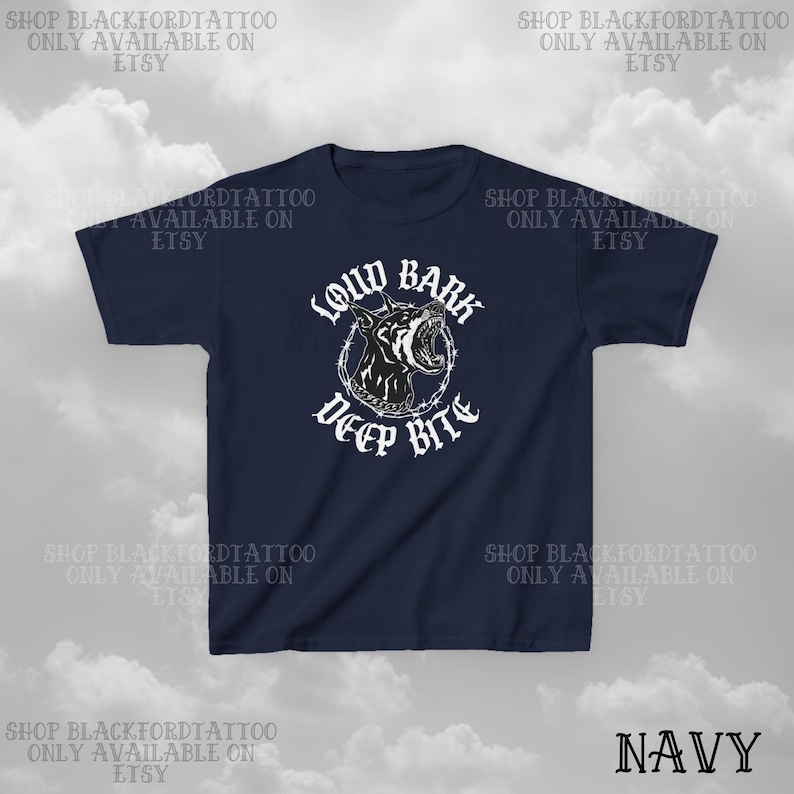 Puede incluir: Camiseta azul marino con un gr&aacute;fico en blanco y negro de la cabeza de un perro gru&ntilde;endo, rodeada de alambre de p&uacute;as, con las palabras "LOUD BARK DEEP BITE" en blanco. La palabra "NAVY" est&aacute; en la parte inferior derecha. El nombre de la tienda Etsy tambi&eacute;n est&aacute; impreso.