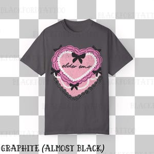 May include: Graphite-colored t-shirt featuring a pink heart-shaped design with the words "elder emo." The heart is decorated with black bows and a black lace border. The shirt's color is described as "almost black."