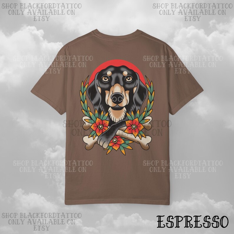 K&ouml;nnte beinhalten: Espressofarbenes T-Shirt mit einer Hundeillustration mit rotem Kreis, Lorbeerkranz, Blumen und gekreuzten Knochen. Der Text "SHOP BLACKFORDTATTOO ONLY AVAILABLE ON ETSY" ist um das Design herum gedruckt.