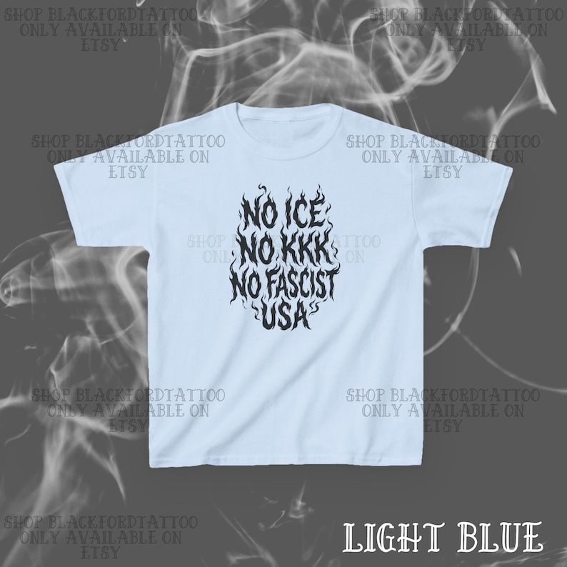 May include: Light blue t-shirt with the text "NO ICE, NO KKK, NO FASCIST, USA" in a stylized black font. The shirt has short sleeves and a crew neck. The Etsy shop name is printed around the shirt.