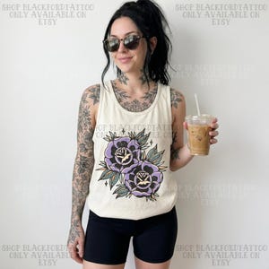 Może przedstawiać: Kremowy top bez rękawów z fioletowym motywem róży i zielonymi liśćmi. Na górze nadrukowano tekst "SHOP BLACKFORDTATTOO ONLY AVAILABLE ON ETSY". Modelka ma na sobie czarne szorty i okulary przeciwsłoneczne.