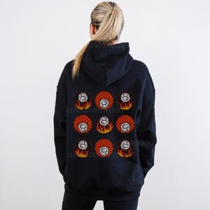 May include: Black hooded sweatshirt with a pattern of nine red and white checkered 8-ball designs with flames on a black background.