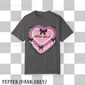 May include: Dark grey t-shirt featuring a pink heart-shaped graphic with the text "elder emo". The graphic includes black bows and a lace-like border. The shirt's color is described as "Pepper (Dark Grey)".