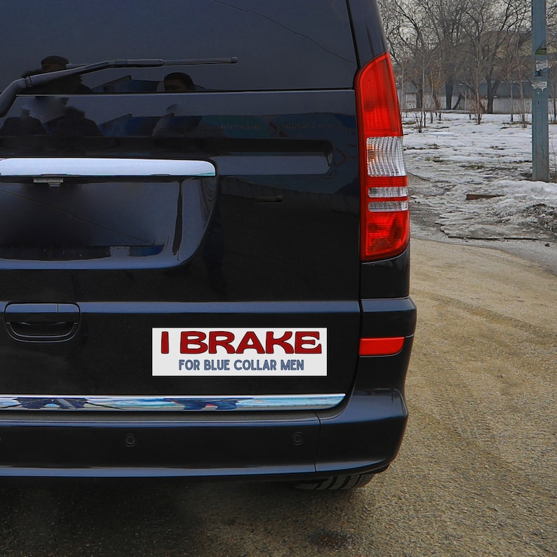 Op de afbeelding: Een zwarte minivan met een witte bumper sticker waarop staat "I Brake For Blue Collar Men".