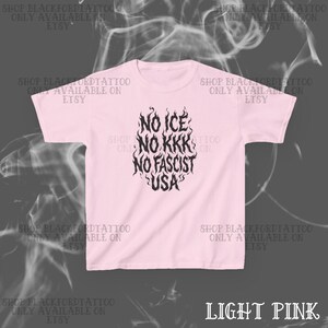 May include: Light pink t-shirt with the text "NO ICE, NO KKK, NO FASCIST, USA" in a black, flame-like design. The shirt also has the text "SHOP BLACKFORDTATTOO ONLY AVAILABLE ON ETSY" repeated around the shirt.